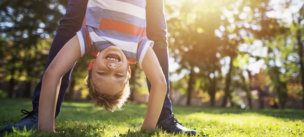 a kid hanging upside down enjoying the yard